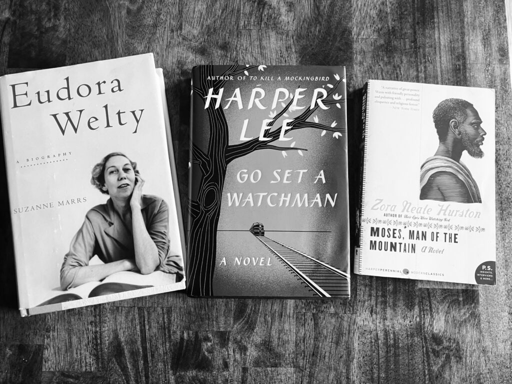 A black-and-white picture of books including a biography of Eudora Welty, Harper Lee's Go Set a Watchman, and Zora Neale Hurston's Moses, Man of the Mountain